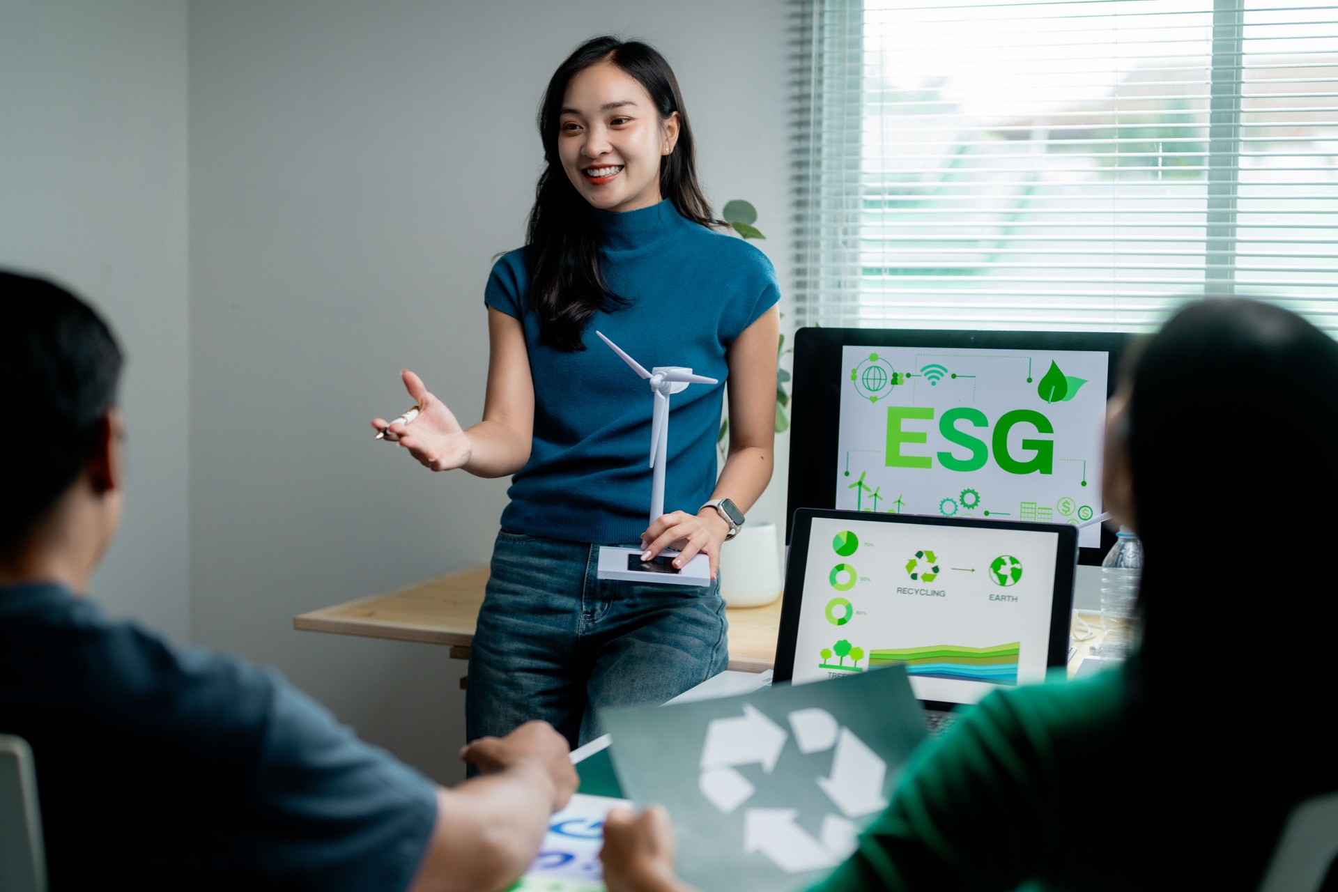 Young adult presenting ESG concepts with visual aids in a modern office setting